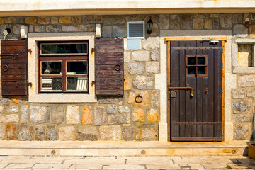 Authentic house with a stone wall, with a beautiful old window and brown shutters, background.
