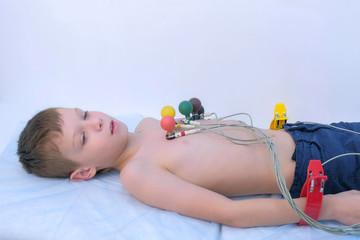 Doctor cardiologist preparing child boy to cardiogram heart procedure, side view. Woman...