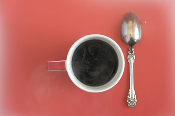 cup with coffee silver spoon on red background