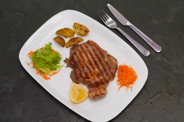 Grilled beef or veal meat steak with lemon, carrots, lettuce and potatoes. Juicy and very tasty dish of Italian cuisine