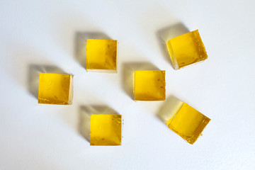 Yellow apple jelly cubes on a white background. Top view