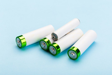 many new and used batteries of different shapes, AA, round batteries on a blue background.