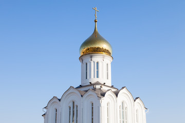 The church is white with a golden dome and a Russian cross on top against a clear blue sky on a summer day. The place of power and faith of Christians professing the religion of proclamation.