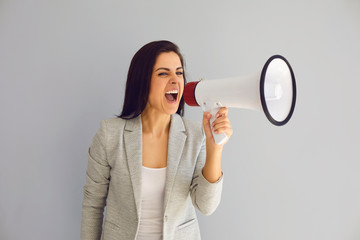 Hispanic woman with a loudspeaker shouts announces news protest on a gray background.