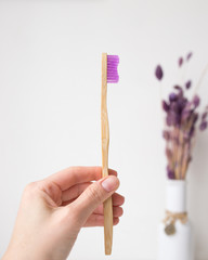 pink bamboo toothbrush in the hand and flowers
