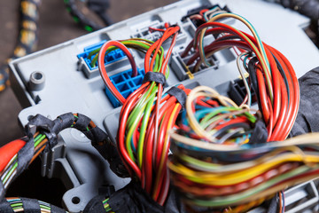 A bunch of multi-colored electrical wires - blue, green, red and yellow, rewound with insulating tape in the nodes of the car during network repair by an engineer or mechanic in a service or workshop.