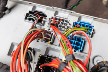 The back of the metal casing of the device with white, black and blue connectors with connected multi-colored electrical wires for the repair of the mains power.
