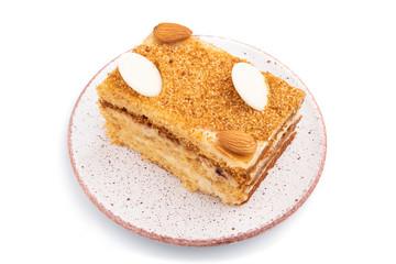 Honey cake with milk cream, caramel, almonds isolated on a white background. Side view.