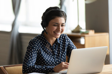 Head shot attractive happy friendly indian woman sitting at desk, holding video call with friends...