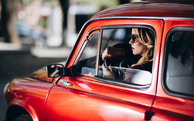 Caucasian blonde woman in red retro car driving at night in james bond style