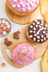 Homemade glazed and decorated easter pies with chocolate eggs and rabbits on a white concrete background. top view, close up.