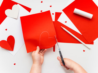 Kid makes Mother's Day or Valentine's Day greeting card. DIY holiday card with red paper volumetric...