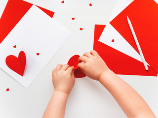 Kid makes Mother's Day or Valentine's Day greeting card. DIY holiday card with red paper volumetric heart, symbol of love. Handicraft made by child with scissors, glue and colored paper.Step 7 of 12