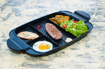 Breakfast, fried steak or cutlet, salad with tomato and green vegetables, croutons, potatoes, egg side view, light background. The concept of healthy diet, diet, menu, good nutrition.