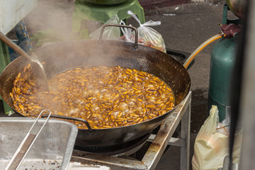 frying worm in a wok to sell at a market in Bangkok, Thailand