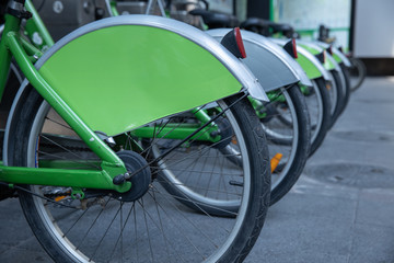 close up view group of green bicycle wheels to rent out for free at parking station.