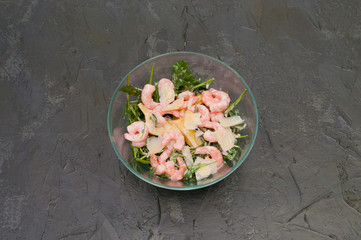 Shrimp, arugula and cheese salad in glass bowl or plate, dark background, copy space, top view