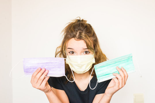 Girl shows protective masks face mask of different colors in hands. Dispoable mask assortment. Mask variety. Lot of masks. Covid -19 prevention.