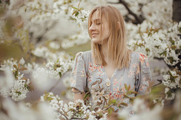 Beautiful girl in a flowering garden. Cherry garden. Summertime Concepts. Closeup Portrait of Positive. happy young woman enjoying smell in a flowering spring garden