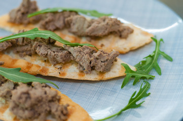 Croutons with paste and arugula. Festive appetizer, New Year's Italian dish. Side and top view, close-up