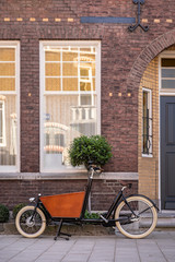 Fototapeta na wymiar Typical Dutch carrier bicycle parked in front of a house. Modern urban parents use these carrier bikes to transport their groceries or children