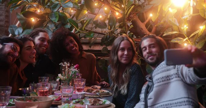 Close up multi-ethnic friends taking selfie with smartphone during meal