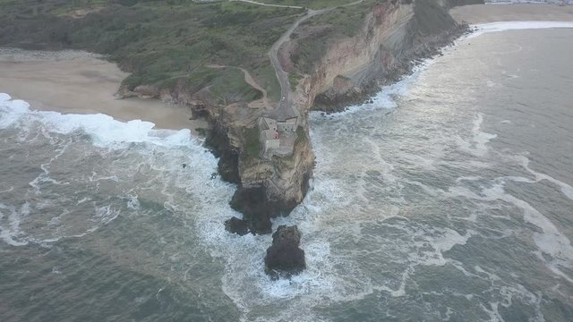 An iconic place on the Atlantic coast, the Mecca of big-wave surfing. View of Nazare's lighthouse in Zon North Canyon, place with the biggest waves in Europe, Nazare, Portugal