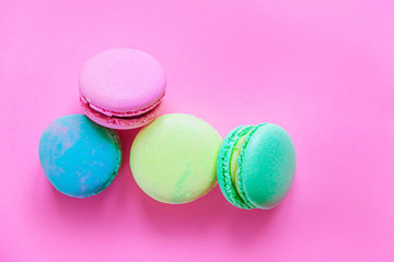 Sweet almond colorful pink blue yellow green macaron or macaroon dessert cake isolated on trendy pink pastel background. French sweet cookie. Minimal food bakery concept. Flat lay top view copy space.