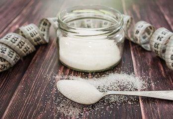 sugar and measuring tape on a wooden background. The concept of weight loss, diet.