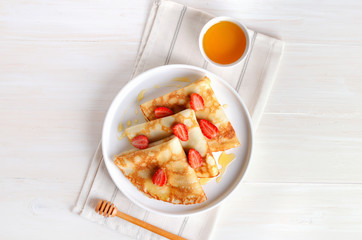 Crepes with strawberry slices and honey