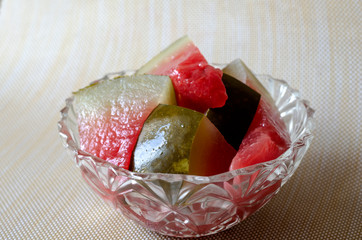 Slices of pickled watermelon in a glass bowl on the table.