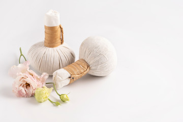 Obraz na płótnie Canvas Cosmetic set for massage with bags of herbs and delicate flower on white background, space for text.