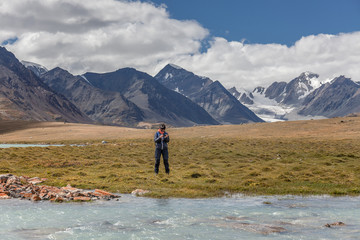 A tourist looks at a photograph of the mountains of the Mongolian Altai on its mobile phone.
