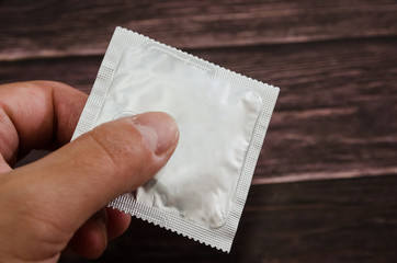 condom in hand on a wooden background. Close-up.