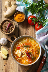 Tukpa soup of Indian cuisine. Hot noodle soup with chicken, ginger, cilantro and spices on a deyven wooden table.