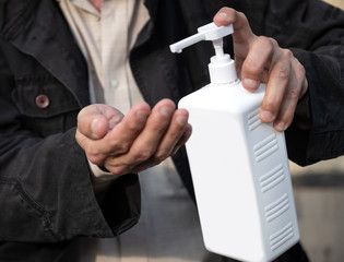 Senior man holding a bottle of hand sanitizer outdoors