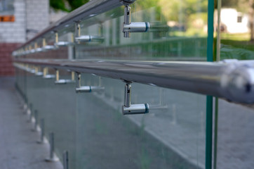 Glass railing for disabled people with chrome handrails.