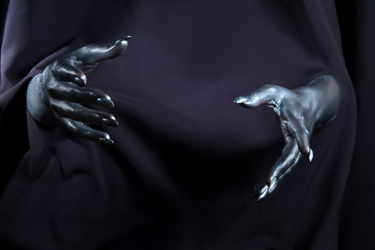 two beautiful man's hands in silver paint on a black background