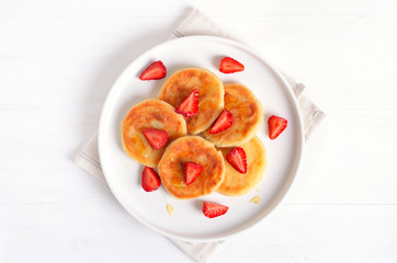 Fototapeta na wymiar Homemade pancakes with cottage cheese and strawberry slices, syrniki