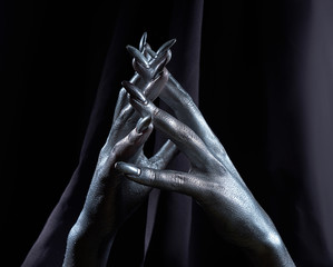 two beautiful man's hands in silver paint on a black background