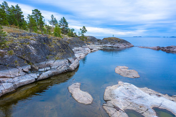 Russia. Karelia. lake Ladoga. The rocky shores of the lake are overgrown with pine trees. Clear water allows you to see the stone bottom. Karelian skerries. Northern nature. Natural scenery.