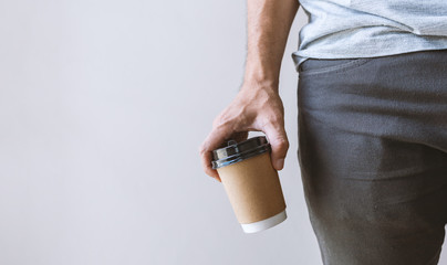 closeup male hand holding a hot coffee cup with soft-focus and over light in the background