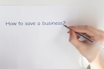 Female hands write on a sheet of paper how to save a business
