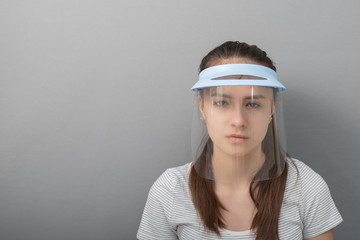 Coronavirus Prevention Young woman in a protective mask screen with a visor on a gray background