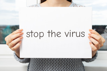 Girl holding a leaf with the words Stop the virus in her hands