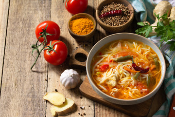 Tukpa soup of Indian cuisine. Hot noodle soup with chicken, ginger, cilantro and spices on a deyven wooden table. Copy space.