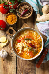 Tukpa soup of Indian cuisine. Hot noodle soup with chicken, ginger, cilantro and spices on a deyven wooden table. Top view flat lay background. Copy space.