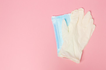 Medical face masks and pair of latex medical gloves isolated on pink background, coronavirus and infection protection.