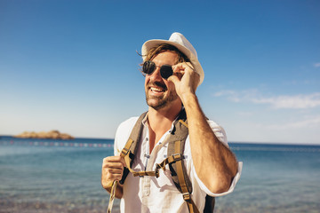 Outdoor fashion portrait of handsome stylish tourist man posing at the beach.