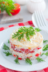 salad with crab sticks, tomatoes, cheese on a white dish, selective focus